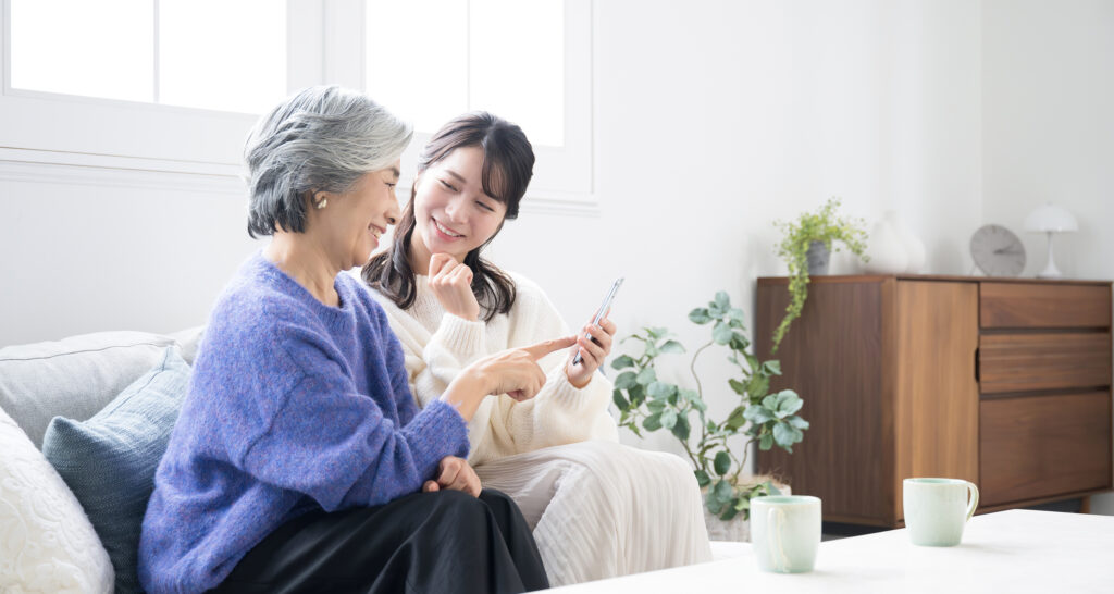 自宅で孫とスマホを見て笑顔のシニア女性