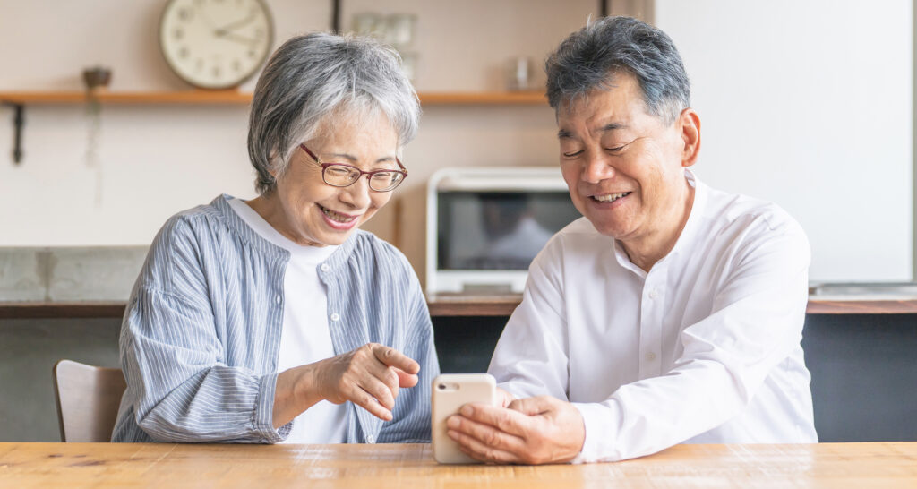夫婦が笑顔で一つのスマートフォンを見る