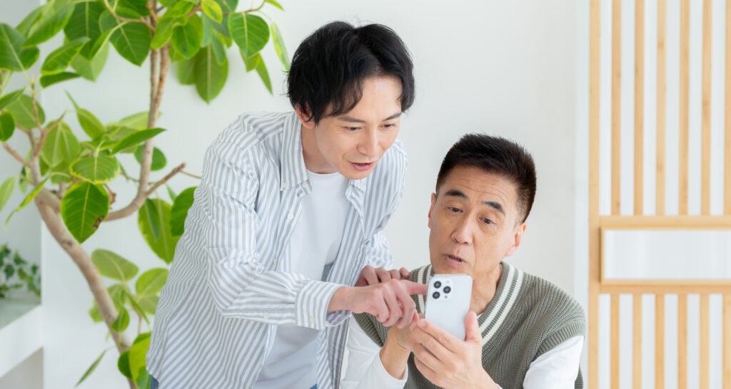家族にスマートフォンの説明を受けるシニア男性