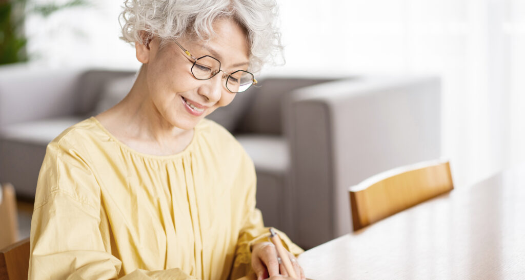 笑顔で日記を書くシニア女性