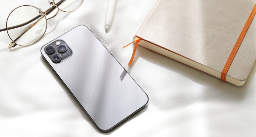 優しい日差しを受けるスマートフォンと日記と眼鏡