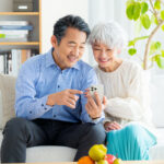 自宅のリビングで夫婦でスマートフォンを見て楽しんでいる様子