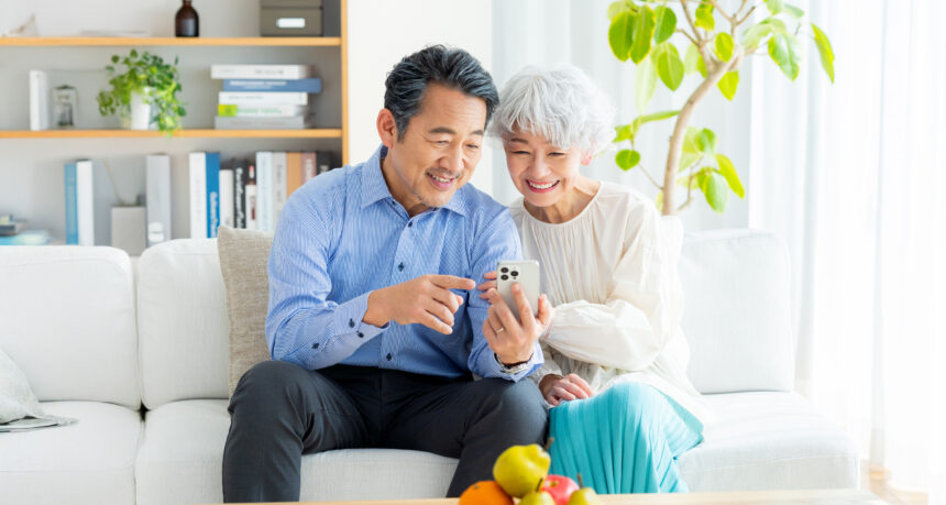 自宅のリビングで夫婦でスマートフォンを見て楽しんでいる様子