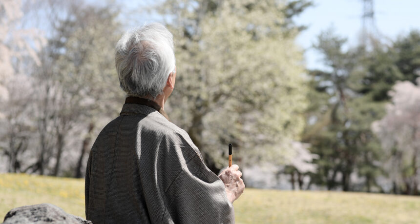 自然の中で俳句を書くシニア男性の後ろ姿