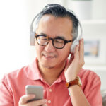スマートフォンの音楽をヘッドフォンで聴くシニア男性