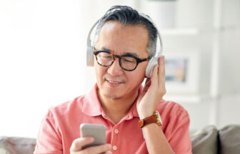 スマートフォンの音楽をヘッドフォンで聴くシニア男性
