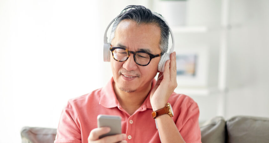 スマートフォンの音楽をヘッドフォンで聴くシニア男性