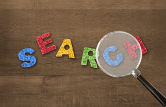 積み木のアルファベットでSEARCHの文字を虫眼鏡で除いている様子