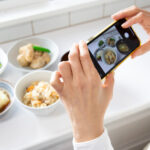 スマートフォンで料理写真を丁寧に撮影している様子