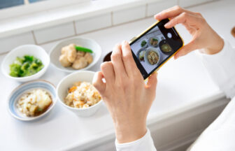 スマートフォンで料理写真を丁寧に撮影している様子