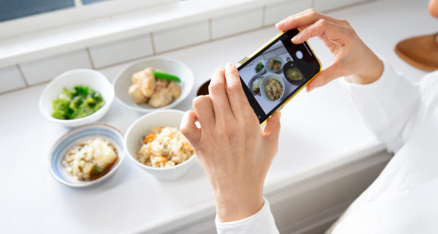 スマートフォンで料理写真を丁寧に撮影している様子