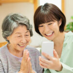 祖母と孫が一緒にスマートフォンを笑顔で見る