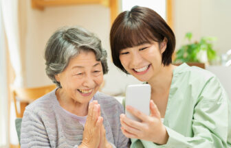 祖母と孫が一緒にスマートフォンを笑顔で見る