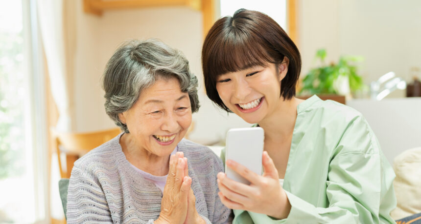 祖母と孫が一緒にスマートフォンを笑顔で見る