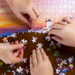 美しい景色のジグソーパズルをする二人の手