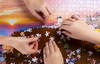 美しい景色のジグソーパズルをする二人の手