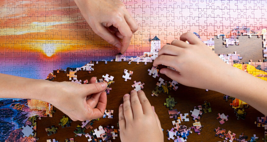 美しい景色のジグソーパズルをする二人の手