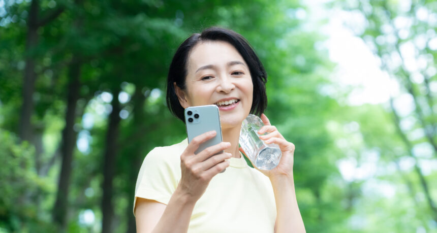 スマートフォンを片手にウォーキングをするミドル女性