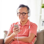 スマートフォンで音声を楽しむヘッドフォンをしたミドル日本人男性