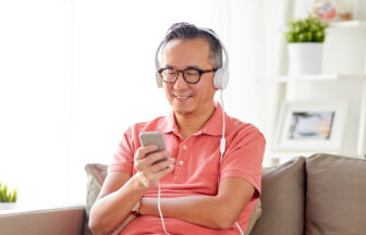 スマートフォンで音声を楽しむヘッドフォンをしたミドル日本人男性