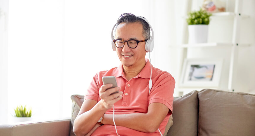 スマートフォンで音声を楽しむヘッドフォンをしたミドル日本人男性