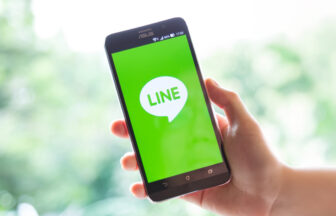 手に持つスマートフォンの画面にLINEの起動画面