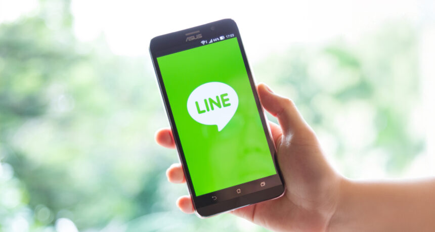 手に持つスマートフォンの画面にLINEの起動画面