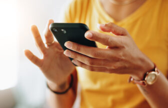スマートフォンで文字を入力する女性の手元