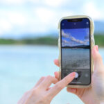 スマートフォンできれいな海の景色を撮影する女性