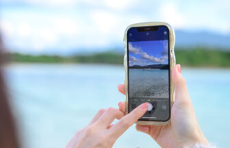 スマートフォンできれいな海の景色を撮影する女性