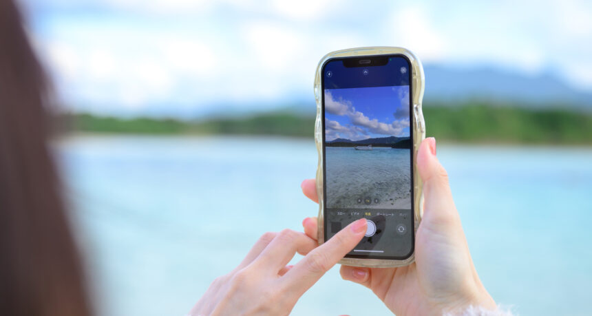 スマートフォンできれいな海の景色を撮影する女性