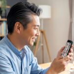 日本人ミドル男性が自宅でスマートフォンを使って　オンラインで複数の人とと会話をしている様子