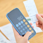 スマートフォンで買い物した金額を計算する女性