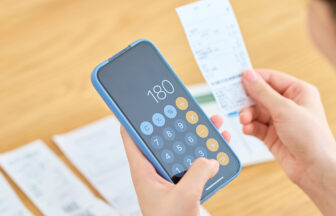 スマートフォンで買い物した金額を計算する女性