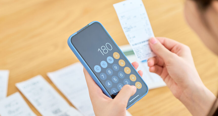 スマートフォンで買い物した金額を計算する女性