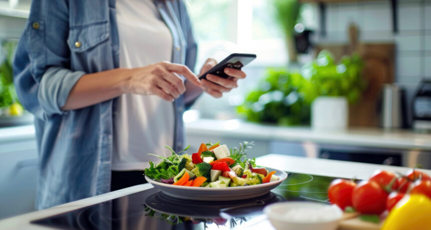 キッチンでスマートフォンでレシピを見て料理をしている様子