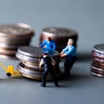 ミニチュアの人形がお金を動かしているイメージ