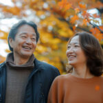 紅葉の下で日本人ミドルの男女が歩いている