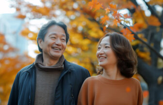 紅葉の下で日本人ミドルの男女が歩いている