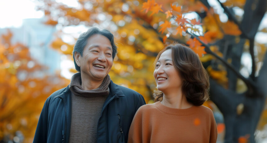 紅葉の下で日本人ミドルの男女が歩いている