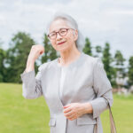 きれいな芝生の上でガッツポーズとする日本人シニア女性