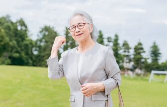 きれいな芝生の上でガッツポーズとする日本人シニア女性