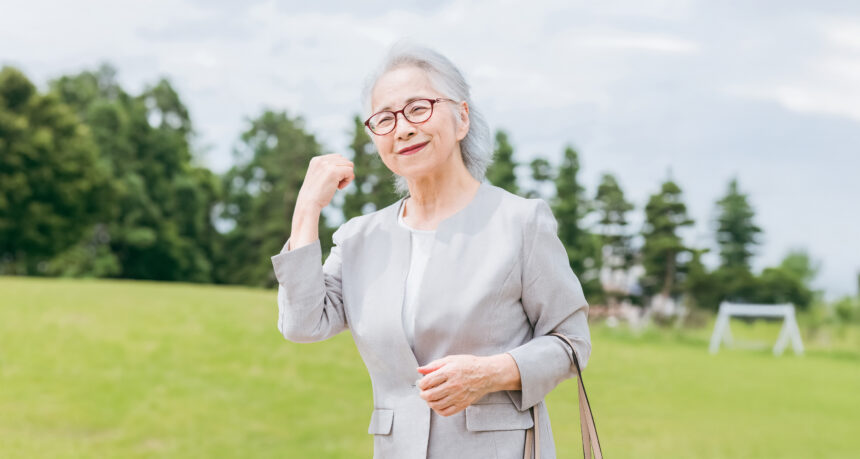 きれいな芝生の上でガッツポーズとする日本人シニア女性