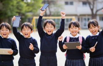 男女５人の子どもたちが横1列に並び、タブレットやスマートフォンを掲げて元気よくガッツポーズをしている
