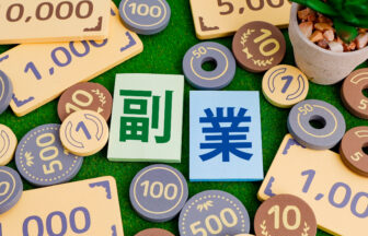 おもちゃのお金と積み木にプリントされた副業の文字