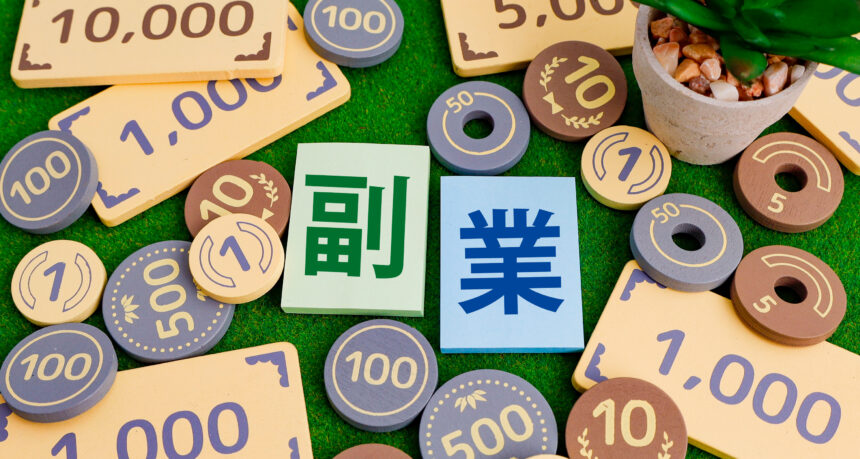 おもちゃのお金と積み木にプリントされた副業の文字